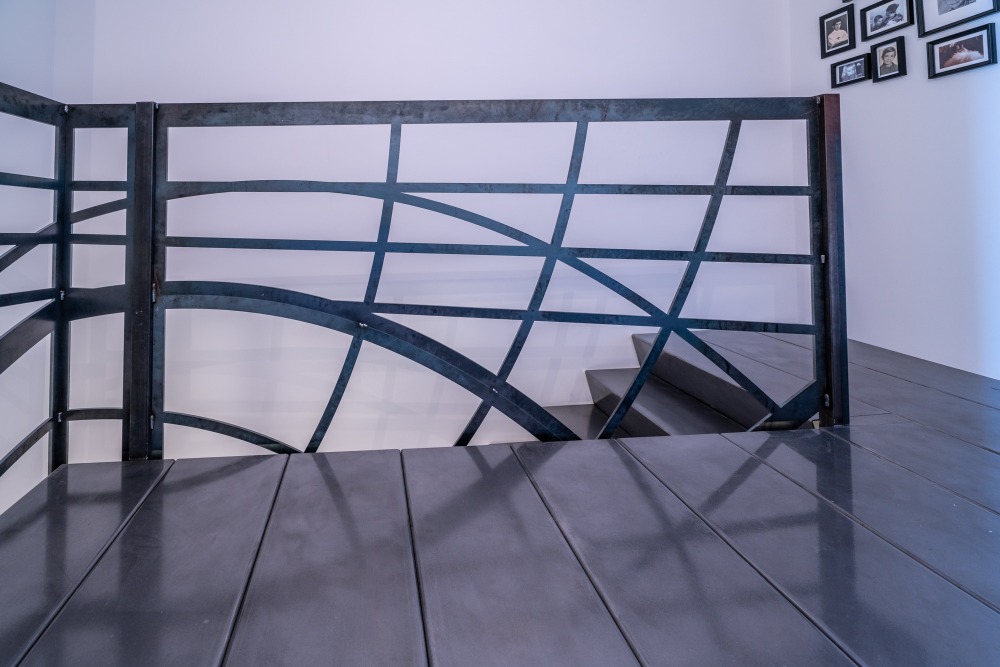 Le palier conçu comme une plateforme en fer forgé robuste, intégrée harmonieusement au mur, offrant un espace d'arrêt minimaliste et moderne au milieu de l'escalier.